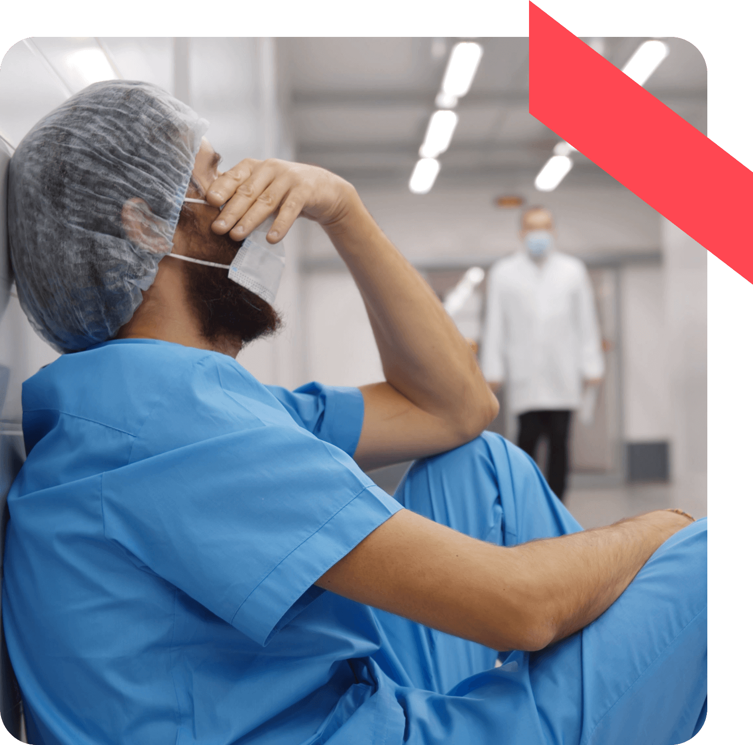 Exhausted healthcare professional in scrubs sitting down to rest in a hospital corridor